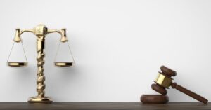 A golden scale of justice and a wooden gavel resting on a dark surface, symbolizing legal balance and authority in a courtroom setting.