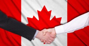 Two hands shaking in front of the Canadian flag, symbolizing a business agreement or partnership in Canada.
