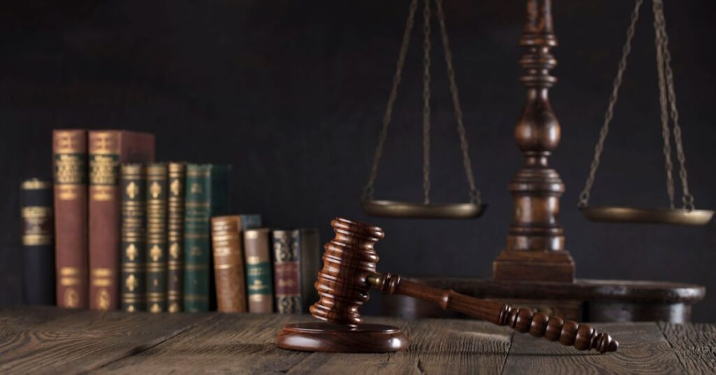 A stack of legal books and a scale of justice on a dark background, symbolizing the importance of understanding legal principles to prevent pitfalls in M&A transactions.