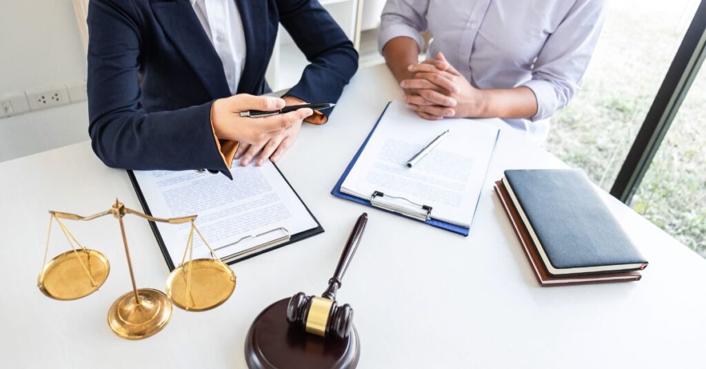 Two professionals reviewing documents with a gavel and scales of justice on a table, symbolizing legal considerations for business expansion across Canada.