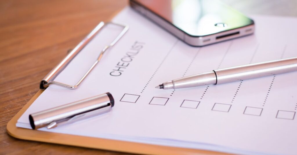 A clipboard with a checklist and a pen resting on it, alongside a smartphone, representing the essential legal checklist for Canadian entrepreneurs.