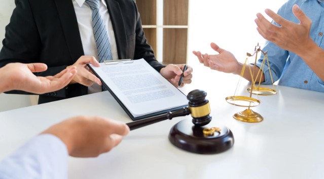 A legal professional reviewing a Confidentiality Agreements document with a gavel and scales of justice on the table during a meeting.
