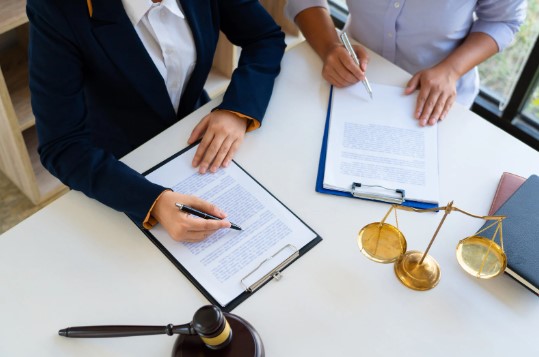 Two professionals reviewing documents with a scale of justice on the table, symbolizing legal aspects of fundraising.