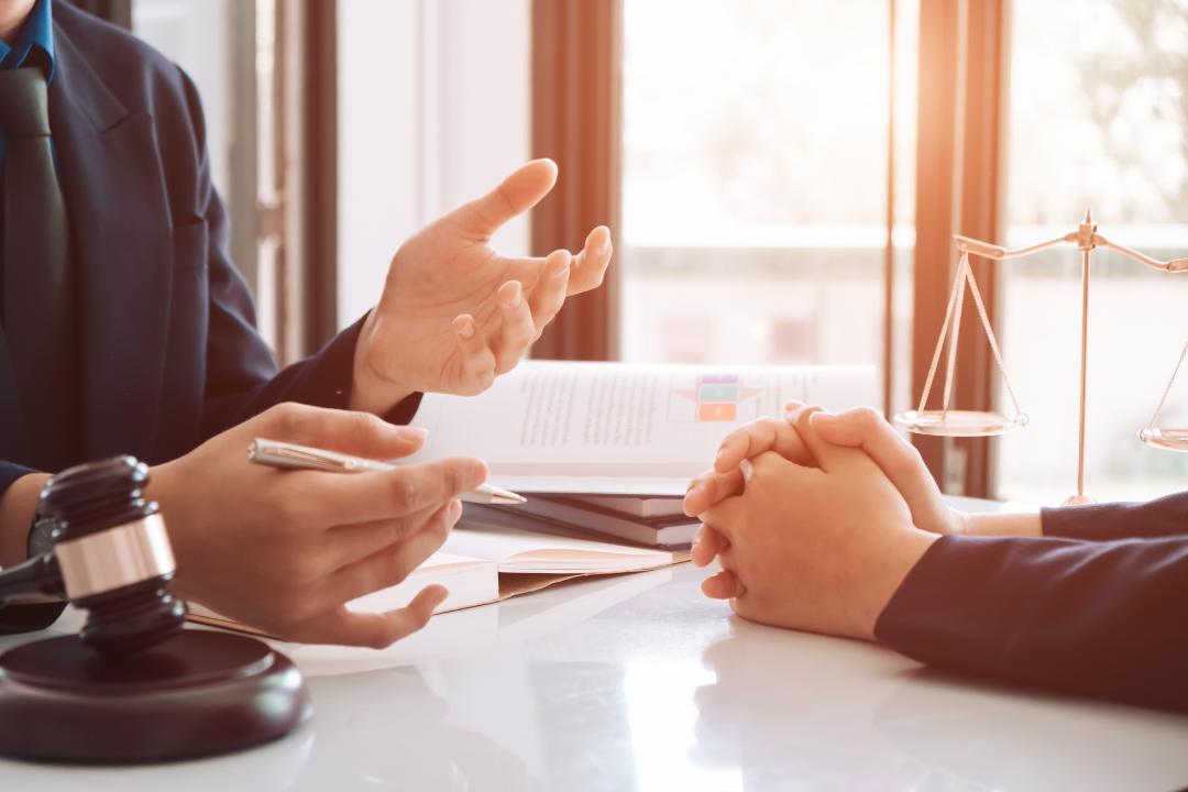 Franchise lawyer consulting with a client across a desk, discussing legal documents with justice scales and gavel in view.