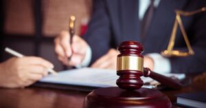 Close-up of a lawyer guiding a client through legal paperwork with a gavel in focus, representing how to prepare a franchise disclosure in Toronto.