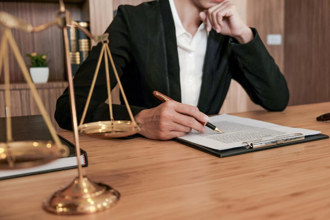Lawyer reviewing financial documents for preparing an audited Franchise Disclosure Document (FDD) in Ontario, with legal scales in the foreground.