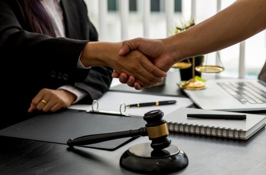 Franchise lawyer and client shaking hands after successful franchise sale agreement review in Toronto office.