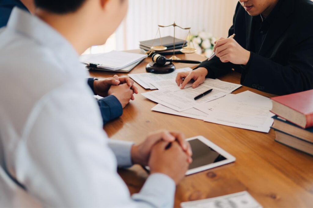 Business clients consulting lawyer about franchise law in Ontario with legal documents, gavel, and scales of justice on desk.