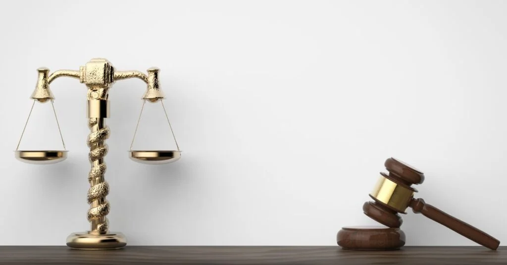 A golden scale of justice and a wooden gavel resting on a dark surface, symbolizing legal balance and authority in a courtroom setting.