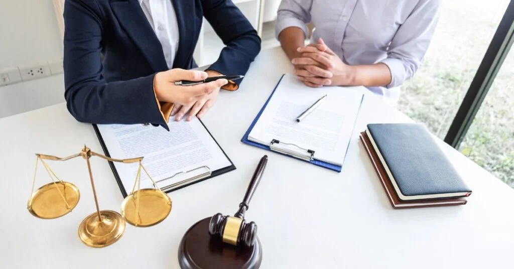 Two professionals reviewing documents with a gavel and scales of justice on a table, symbolizing legal considerations for business expansion across Canada.