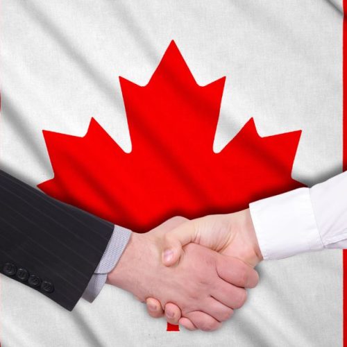 Two hands shaking in front of the Canadian flag, symbolizing a business agreement or partnership in Canada.