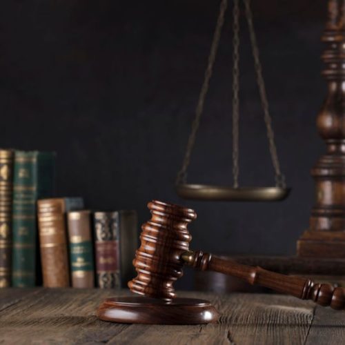A stack of legal books and a scale of justice on a dark background, symbolizing the importance of understanding legal principles to prevent pitfalls in M&A transactions.
