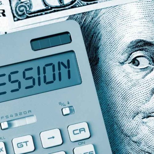 An image featuring a calculator displaying the word "RECESSION" overlaid on a partial view of a U.S. hundred-dollar bill with Benjamin Franklin's portrait.
