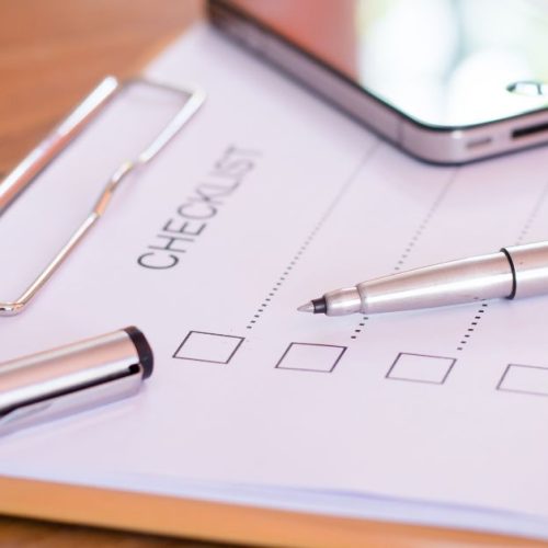 A clipboard with a checklist and a pen resting on it, alongside a smartphone, representing the essential legal checklist for Canadian entrepreneurs.