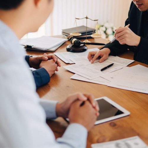 Business clients consulting lawyer about franchise law in Ontario with legal documents, gavel, and scales of justice on desk.