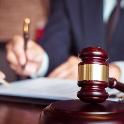 Close-up of a lawyer guiding a client through legal paperwork with a gavel in focus, representing how to prepare a franchise disclosure in Toronto.